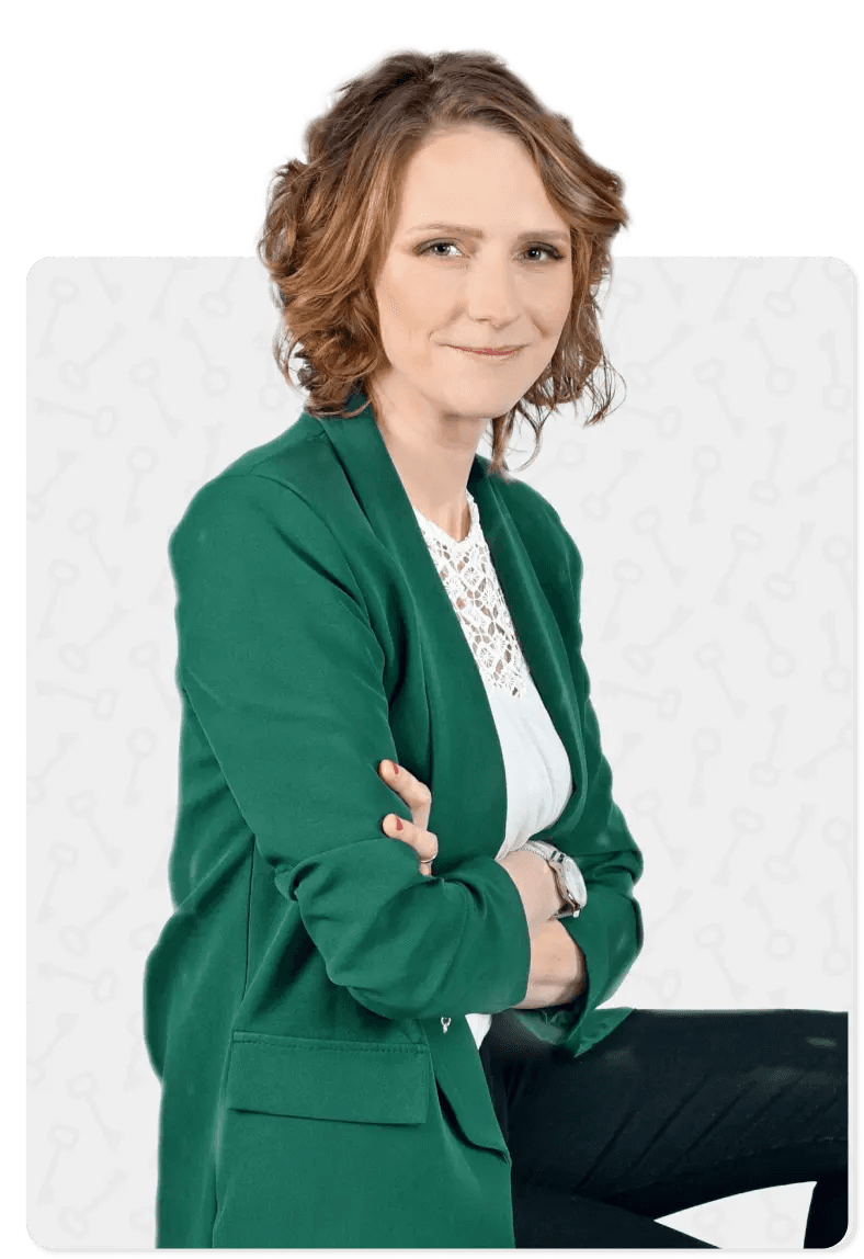 Kobieta z krótkimi blond włosami w zielonej marynarce – copywriterka Słowa Klucze. Ma czerwone paznokcie i srebrny zegarek na nadgarstku.
